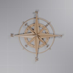 Op de afbeelding: Een lichtbruine houten kompasroos wanddecoratie met een centrale achtpuntige ster, een cirkelvormige ring met kleine ronde uitsparingen en de windrichtingletters N, S, E, W, NE, SE, SW en NW geplaatst rondom de buitenste rand.