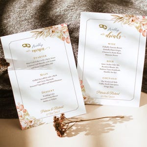 Puede incluir: Dos tarjetas blancas de menú y bebidas de boda con texto dorado, ilustraciones florales y dos anillos dorados. El menú enumera entrantes, platos principales y postres, mientras que la carta de bebidas enumera vinos, cervezas y cócteles para Patricia & Richard, 17/08/2023.