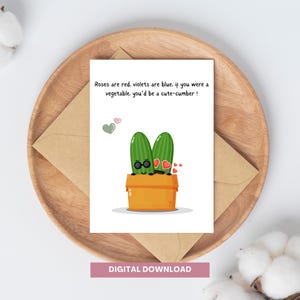 May include: A greeting card with a cute cartoon illustration of two green cucumbers wearing sunglasses and a heart. The text on the card reads "Roses are red, violets are blue. If you were a vegetable, you'd be a cute-cumber!"