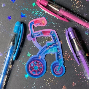A die-cut sticker of a wheeled, rolling walker in shades of purple, pink, and blue. The walker is decorated with stars, constellations, and moon phases.