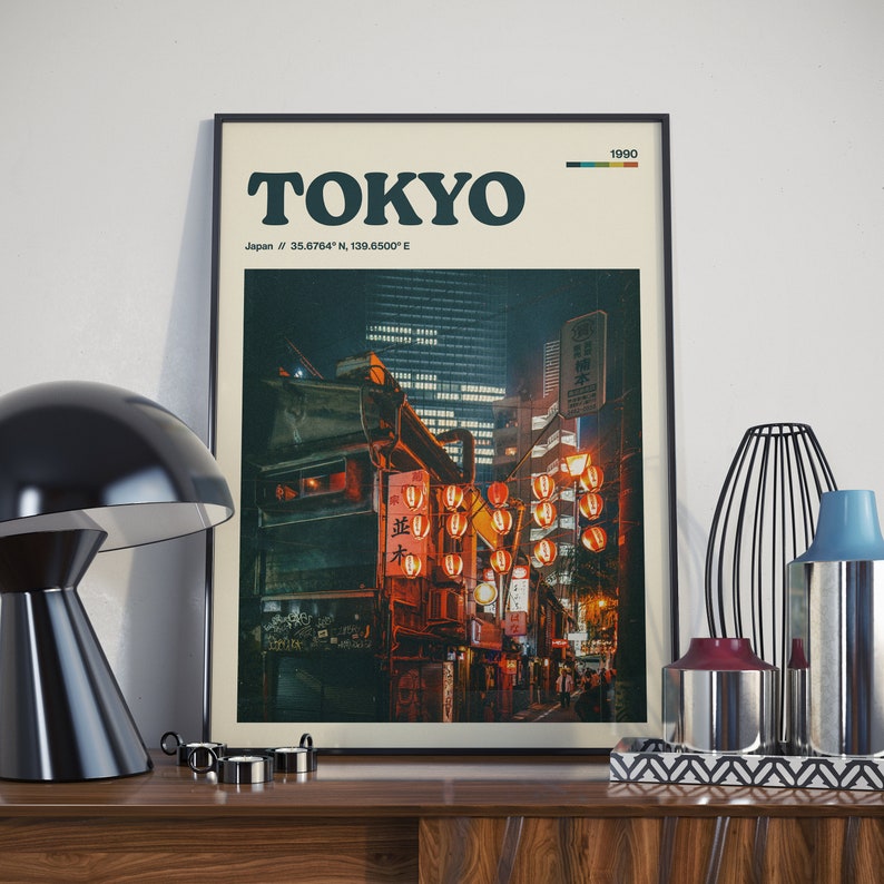 Peut inclure: Une affiche de style vintage avec le mot "TOKYO" en lettres noires et grasses. L'affiche pr&eacute;sente une ville nocturne avec des lanternes rouges et le texte "Japan // 35.68764&deg; N, 139.6500&deg; E" et "1990".