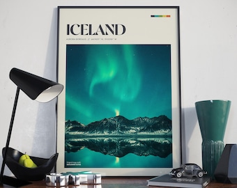 May include: A poster with a black frame featuring a photograph of the Northern Lights reflecting in a lake in Iceland. The poster has the text "ICELAND" and "AURORA BOREALIS / 64.9631° N, 19.0208° W" printed on it.