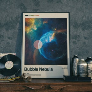 May include: A framed poster featuring a colourful image of the Bubble Nebula, a large star-forming region in the constellation Cassiopeia. The poster has the text "Bubble Nebula" and "NGC 7635" printed on it.