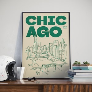 Op de afbeelding: Een ingelijste poster met de tekst CHICAGO en United States in donkergroene inkt op een cr&egrave;mekleurige achtergrond. Het kunstwerk toont een lijntekening van de skyline van Chicago, een rivier met een brug en een verhoogd treinspoor met een trein.