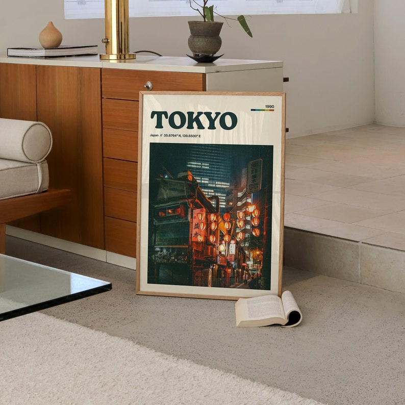 Peut inclure: Une impression encadr&eacute;e avec une photo d'une sc&egrave;ne de rue &agrave; Tokyo, au Japon. La photo montre une rue bord&eacute;e de boutiques et de b&acirc;timents, avec des lanternes rouges suspendues au-dessus. L'impression a un fond blanc avec le mot "TOKYO" en texte noir en haut et les coordonn&eacute;es "35.6874&deg; N, 139.6917&deg; E" en texte noir plus petit en dessous. L'impression comporte &eacute;galement l'ann&eacute;e "1990" dans un petit rectangle color&eacute; dans le coin sup&eacute;rieur droit.