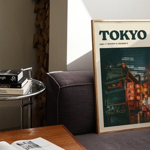 Peut inclure: Une affiche encadr&eacute;e avec une photographie d'une sc&egrave;ne nocturne &agrave; Tokyo, au Japon. L'affiche porte le texte "TOKYO" en lettres noires grasses et les coordonn&eacute;es "Japan // 35.6764&deg; N, 139.6500&deg; E" en lettres noires plus petites. La photographie montre une sc&egrave;ne de rue avec des b&acirc;timents, des lampadaires et des lanternes rouges.