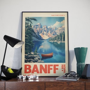 May include: Vintage travel poster featuring a scenic view of Banff National Park in Canada. The poster depicts a turquoise lake surrounded by snow-capped mountains and lush green trees. A red canoe is floating on the water. The text "BANFF NATIONAL PARK" is printed in red and white.