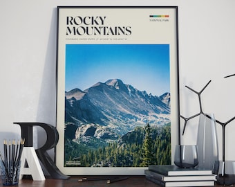 May include: A black framed poster with a white background and the text "ROCKY MOUNTAINS NATIONAL PARK" in black. The poster features a photograph of a mountain range with a blue sky and green trees.