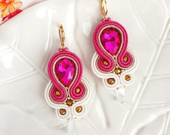 May include: A pair of pink and white earrings with a large pink crystal in the center. The earrings are made with gold wire and beads.
