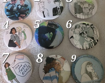 May include: Nine round button pins with various illustrations. The pins feature cartoon characters, text, and a rainbow flag. The pins are white with black outlines.