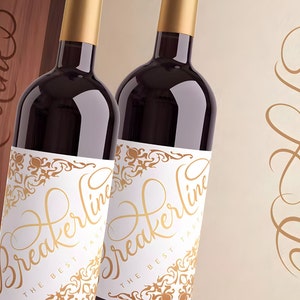 Pu&ograve; includere: Due bottiglie di vino rosso con etichette dorate che recitano "Breakerline The Best Taste". Le bottiglie sono davanti a una scatola di legno con lo stesso testo sul lato.