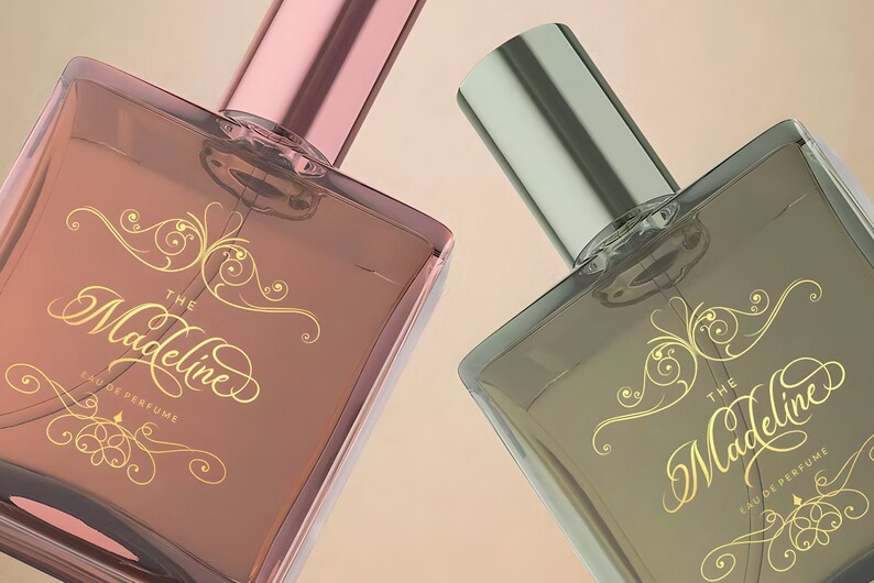 Pu&ograve; includere: Due flaconi di profumo in vetro con scritta dorata "The Madeline Eau de Perfume". I flaconi hanno un design decorativo dorato e sono su uno sfondo beige.