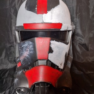 May include: A black and red helmet with white paint accents. The helmet has a visor and a chin guard. The helmet is a replica of a Star Wars character.