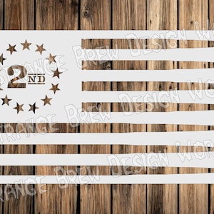 Può includere: Uno stencil bianco di una bandiera americana con 13 strisce e un cerchio di stelle. Il cerchio di stelle contiene il numero "2" e la parola "ND". Il testo "Strange Brew Design Work" è ripetuto nell'immagine.