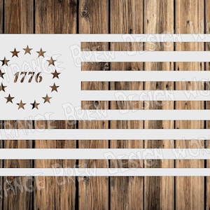 May include: A white stencil of the American flag with 13 stripes and a circle of 13 stars with the year 1776 inside. The stencil is on a wooden background.