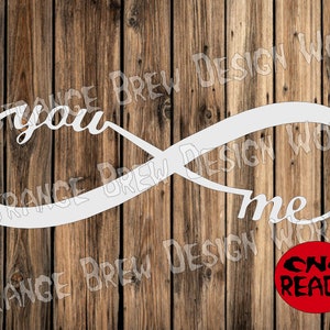 Peut inclure: Symbole d'infini blanc avec les mots "you" et "me" écrits à l'intérieur. Le symbole est sur un fond en bois avec un cercle rouge qui dit "CNC READY" en blanc.