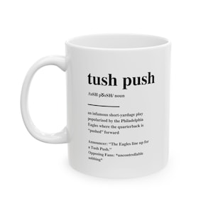 Może przedstawiać: Biały ceramiczny kubek z napisem "tush push" czarną, pogrubioną czcionką. Kubek zawiera definicję terminu, w tym jego pochodzenie z Philadelphia Eagles. Humorystyczny prezent dla fanów futbolu.