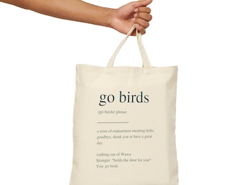 May include: A white canvas tote bag with a green graphic that says "go birds" and defines the phrase as a term of endearment meaning hello, goodbye, thank you, or have a great day. The graphic also includes an example of the phrase being used in a conversation.