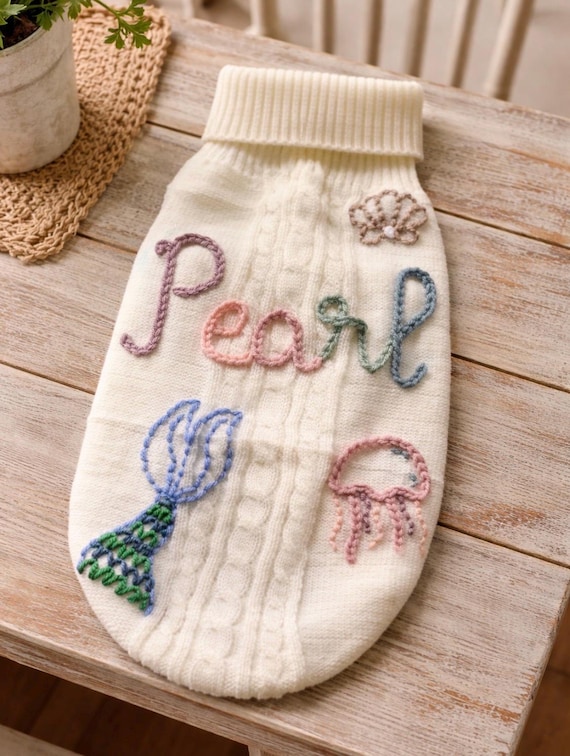 A genuinely hand-embroidered mermaid sweater sized for small dogs/puppies with a custom name — real needle-and-thread craft skill, not a print, and the combo of "mermaid" + "pet couture" + "keepsake" is wonderfully specific.