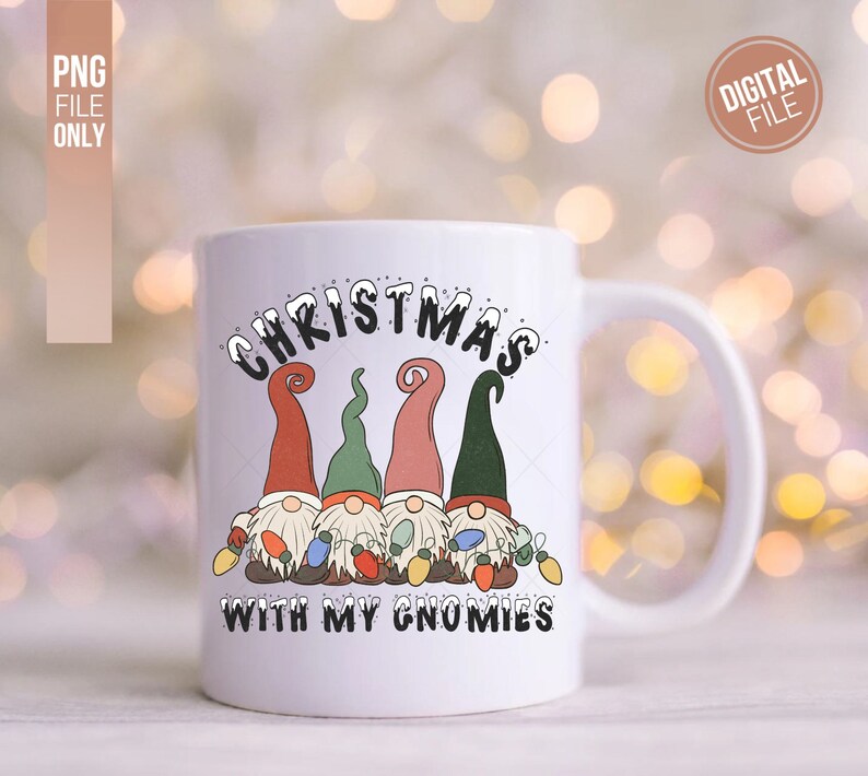 May include: A white ceramic mug featuring a graphic of four gnomes wearing red, green, and pink hats, holding colorful Christmas lights. The text above reads CHRISTMAS and the text below reads WITH MY GNOMIES in black, snow-capped lettering.