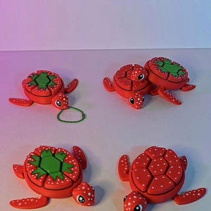 May include: Four red and green turtle keychains with white polka dots. Each turtle has a small chain attached to it.
