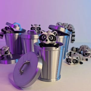 May include: A group of small, gray and white raccoon figurines are placed inside silver trash cans. The trash cans have lids and one lid is open. The figurines are all in different poses.