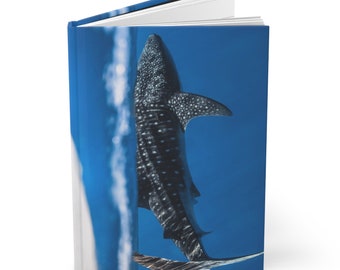 May include: A book cover featuring a close-up of a whale shark swimming in blue water. The shark is facing away from the camera, with its tail fin visible in the bottom right corner of the image.