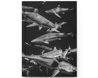 May include: A black and white photograph of a school of sharks swimming in a dark, murky water. The sharks are all facing the same direction and appear to be swimming in a tight formation.