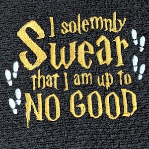 May include: A black textured fabric featuring gold embroidered text that reads I solemnly Swear that I am up to NO GOOD. The embroidery is flanked by small white stitched footprints on both the left and right sides of the central lettering.
