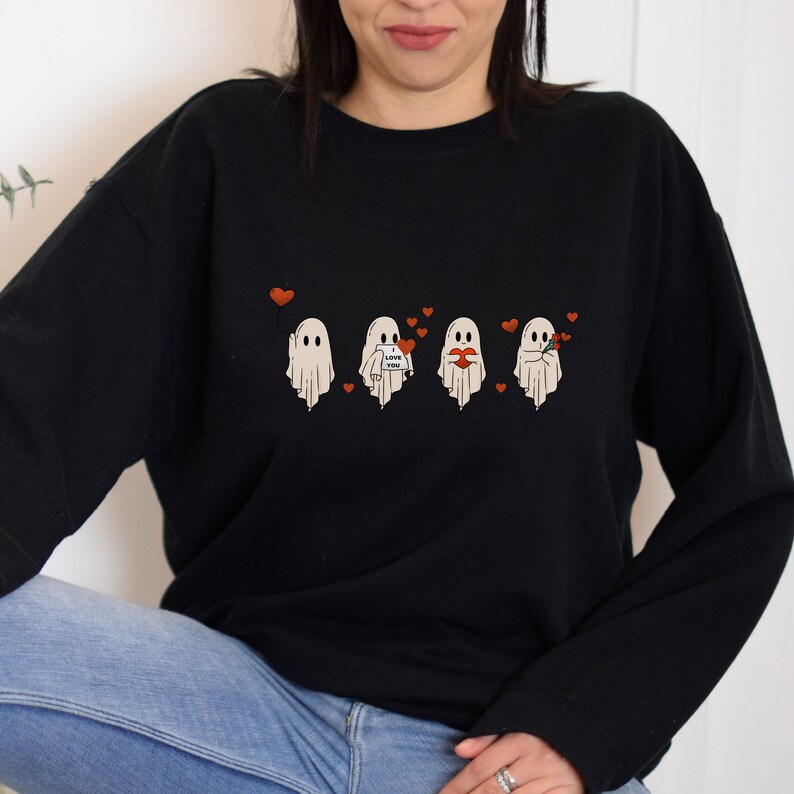 May include: Black sweatshirt with a graphic of four ghosts wearing different expressions of love. The ghosts are holding a heart, a bouquet of flowers, a balloon, and a sign that says "I love you".