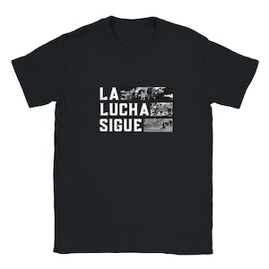 May include: A black short-sleeved t-shirt featuring the white text LA LUCHA SIGUE on the left side. To the right of the text are three stacked black and white photographic panels depicting various protest scenes with people and signs.