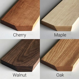 May include: Close-up of four wood samples: cherry, maple, walnut, and oak. Each sample is a light brown to dark brown color and has a unique grain pattern.