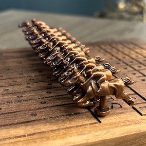 Puede incluir: Un juego de carreras de caballos de madera con una fila de caballos de bronce alineados en la puerta de salida. Los caballos están numerados del 1 al 5.