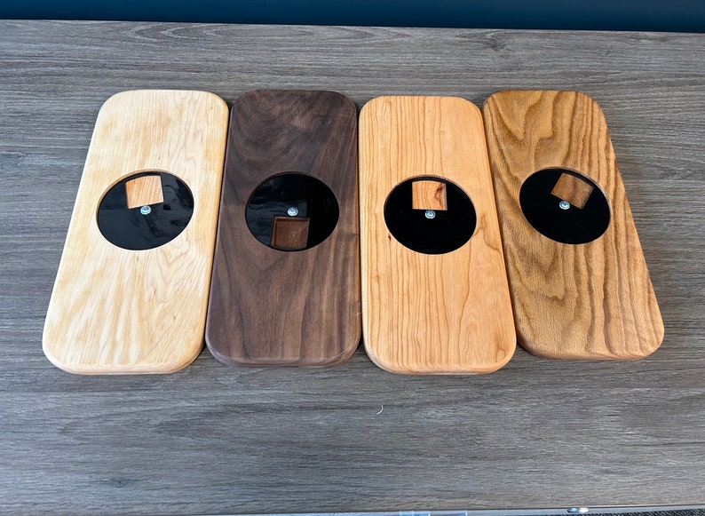 May include: Four wooden coasters with a black circular inlay. The coasters are made of different types of wood, including oak, walnut, and cherry.
