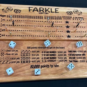 May include: Wooden Farkle score card with dice and scoring rules. The board has spaces for players and scoring, with dice and pegs. The text "FARKLE" is at the top. Includes the text "10,000 points to win".