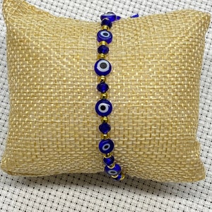 May include: A blue and gold evil eye bracelet with gold beads and blue glass evil eye charms.