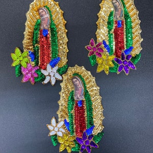 May include: Three embroidered patches featuring the image of the Virgin Mary, surrounded by colorful sequins and flowers. The patches are made of gold, green, red, blue, purple, and white sequins.