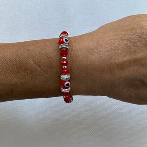 May include: Red beaded bracelet with silver charms and evil eye beads.