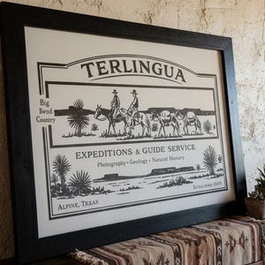 Puede incluir: Impresión enmarcada en negro con la palabra "TERLINGUA" en la parte superior, sobre una ilustración de personas a caballo y animales de carga. La impresión también incluye el texto "EXPEDITIONS & GUIDE SERVICE" y "ALPINE, TEXAS".
