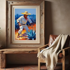 May include: Framed art print depicting a person in a white outfit and straw hat working in a field of blue agave plants. The artwork has a rustic wooden frame and is displayed on a wooden bench. A tan throw blanket rests on a leather chair.