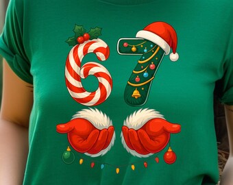 May include: Green t-shirt with a festive Christmas design. The number "6" is a red and white candy cane, and the number "7" is a green pickle decorated with a Santa hat and Christmas ornaments. The design includes red gloves holding ornaments.