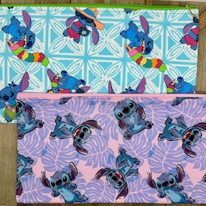 May include: Two rectangular zippered pouches. One is light blue with a pattern of the character Stitch, and the other is pink with a Stitch pattern. Both have a matching zipper and a contrasting color trim.