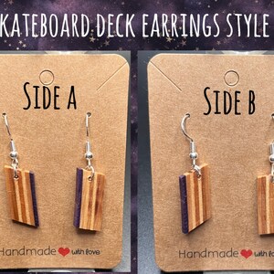 May include: A pair of earrings made from a skateboard deck. The earrings are brown with purple stripes and have silver hooks. The earrings are displayed on a brown card with the words "Side A" and "Side B" written on them. The card also has the words "Handmade with love" written on it.