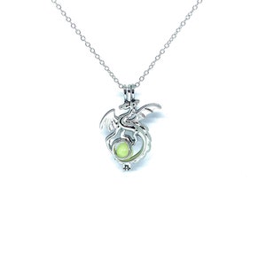 May include: A silver dragon charm necklace with a glowing green orb inside. The necklace has a delicate chain and a lobster clasp.