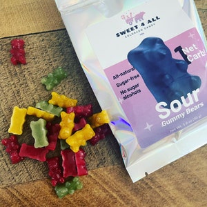 May include: A bag of sour gummy bears with the text "Sweet 4 All Colorado Candy" and "Sour Gummy Bears Net Wt. 1.8 oz (50 g)" on the front. The bag is silver with a holographic finish. The gummy bears are red, green, and yellow.