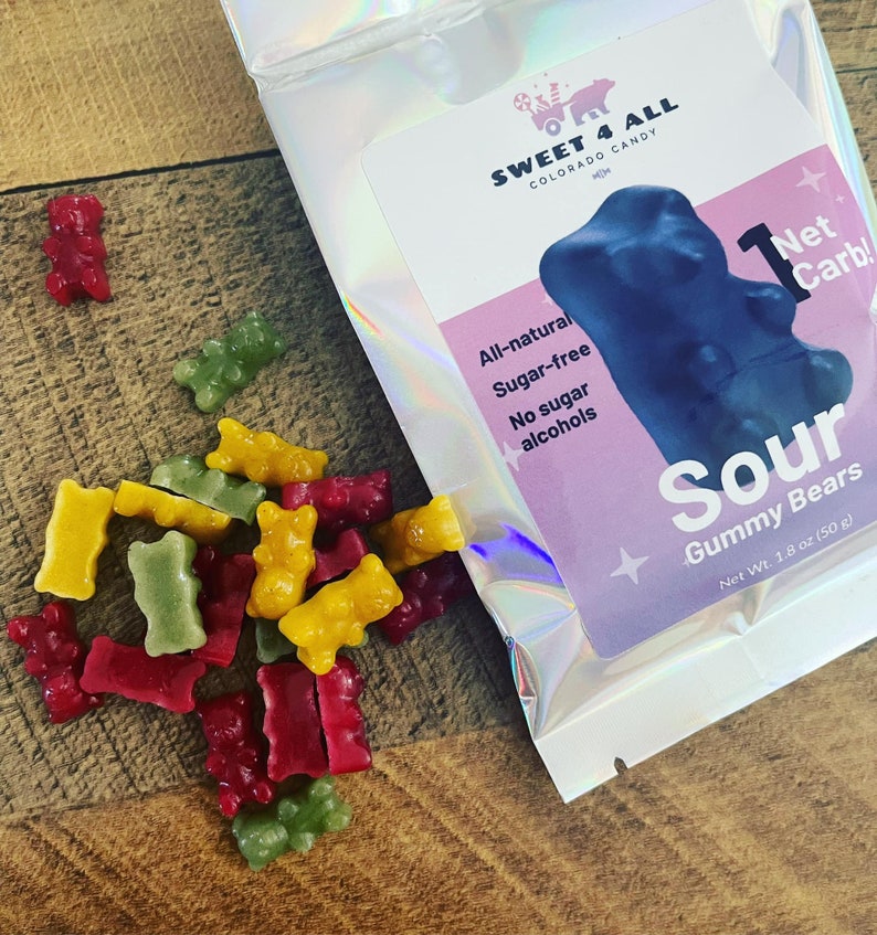 May include: A bag of sour gummy bears with the text "Sweet 4 All Colorado Candy" and "Sour Gummy Bears Net Wt. 1.8 oz (50 g)" on the front. The bag is silver with a holographic finish. The gummy bears are red, green, and yellow.