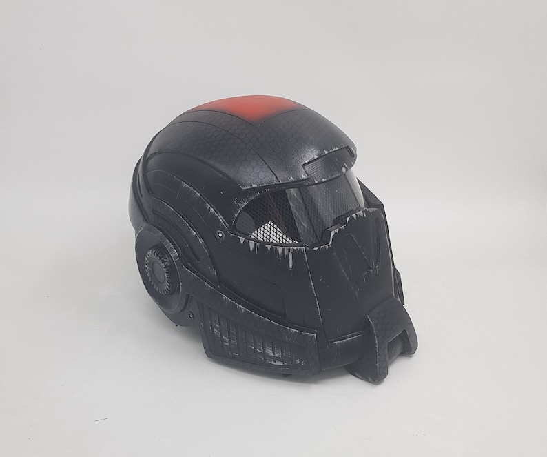 May include: Black helmet with a red stripe on top and a black visor. The helmet has a textured surface and a detailed design.