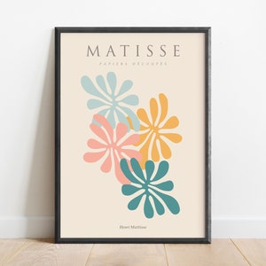 May include: A framed print of a Matisse artwork featuring colorful cut-out paper shapes in shades of blue, pink, and yellow. The title "MATISSE PAPIERS DECOUPES" and the artist's name "Henri Matisse" are printed below the artwork.