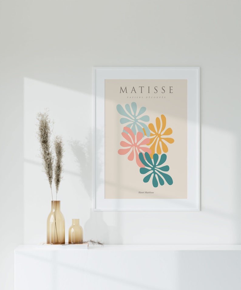 May include: A white framed print with the text "MATISSE PAPIERS DECOUPES" and the artist's name "Henri Matisse" in a light brown font. The print features a colorful abstract design of overlapping teal, pink, yellow, and blue shapes.