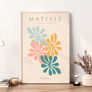 May include: A framed print with a beige background featuring a Matisse-inspired design of four colorful abstract flowers in shades of teal, pink, yellow, and orange. The text "MATISSE PAPIERS DECOUPES Henri Matisse" is printed below the flowers.